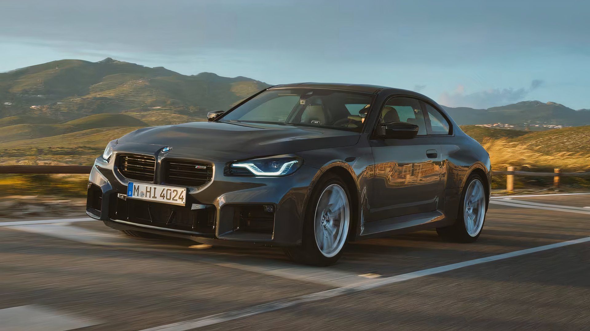 2025 BMW M2 em cinza dirigindo em estrada secundária