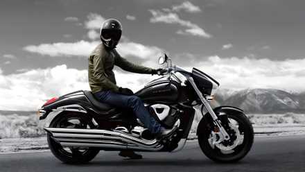 Perfil lateral do Suzuki Boulevard M109R com piloto posando em frente a uma montanha