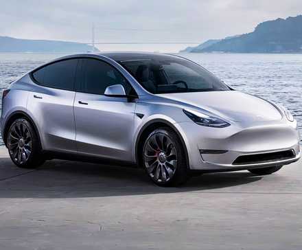 Um pequeno SUV elétrico Tesla Model Y 2021 cinza está estacionado perto da água.
