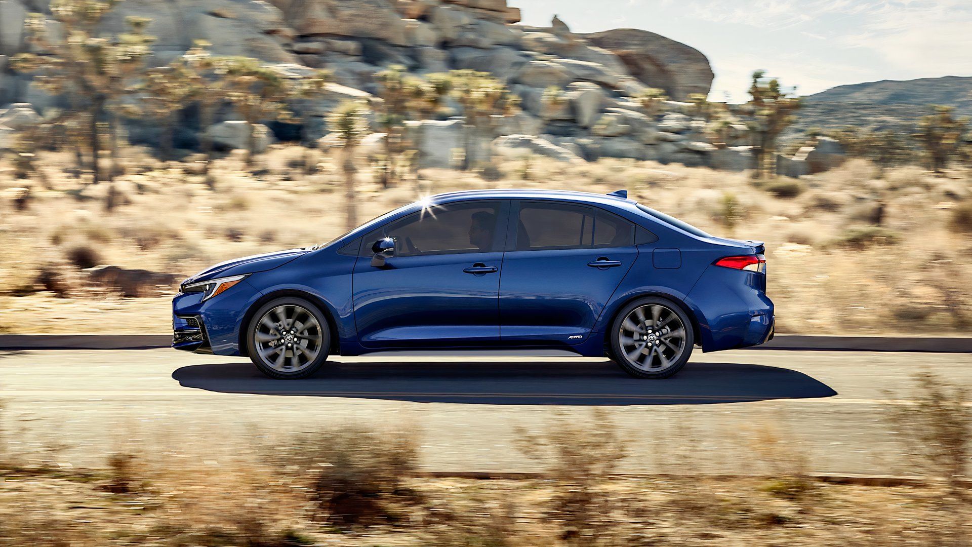 Side profile shot of a blue 2025 Toyota Corolla Hybrid in action