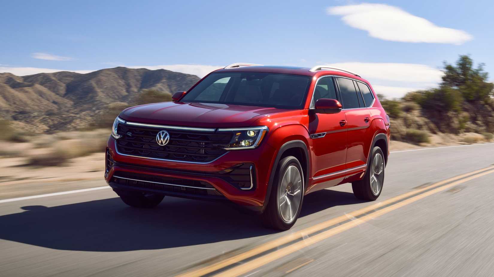 2025 Volkswagen Atlas em vermelho dirigindo na estrada em frente à cordilheira