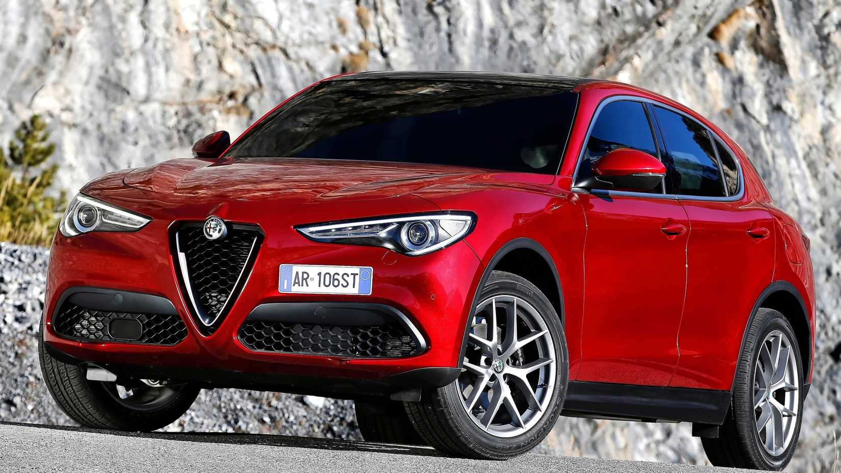 Foto frontal 3/4 de um Alfa Romeo Stelvio 2018 vermelho estacionado em uma estrada de montanha