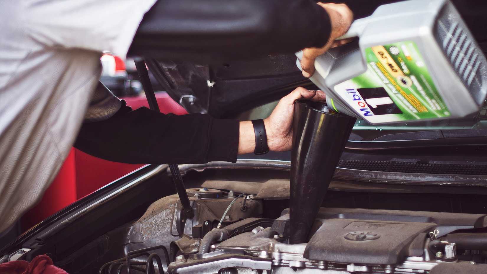 Mechanic puts oil into a car