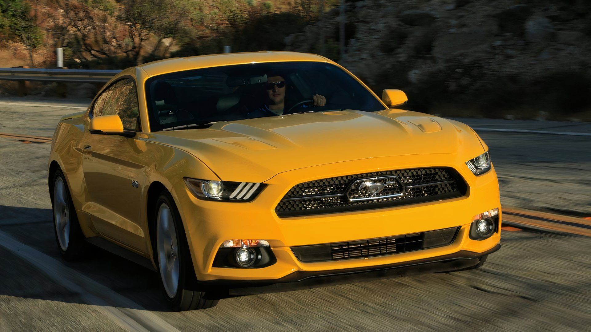 2015 Ford Mustang GT in yellow driving on road