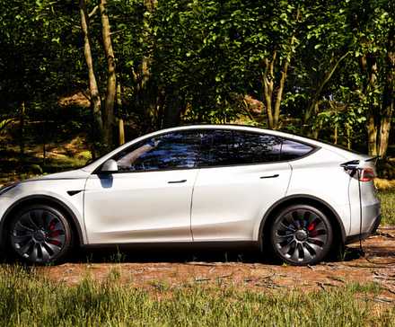 Um pequeno SUV elétrico Tesla Model Y branco está carregando ao ar livre.