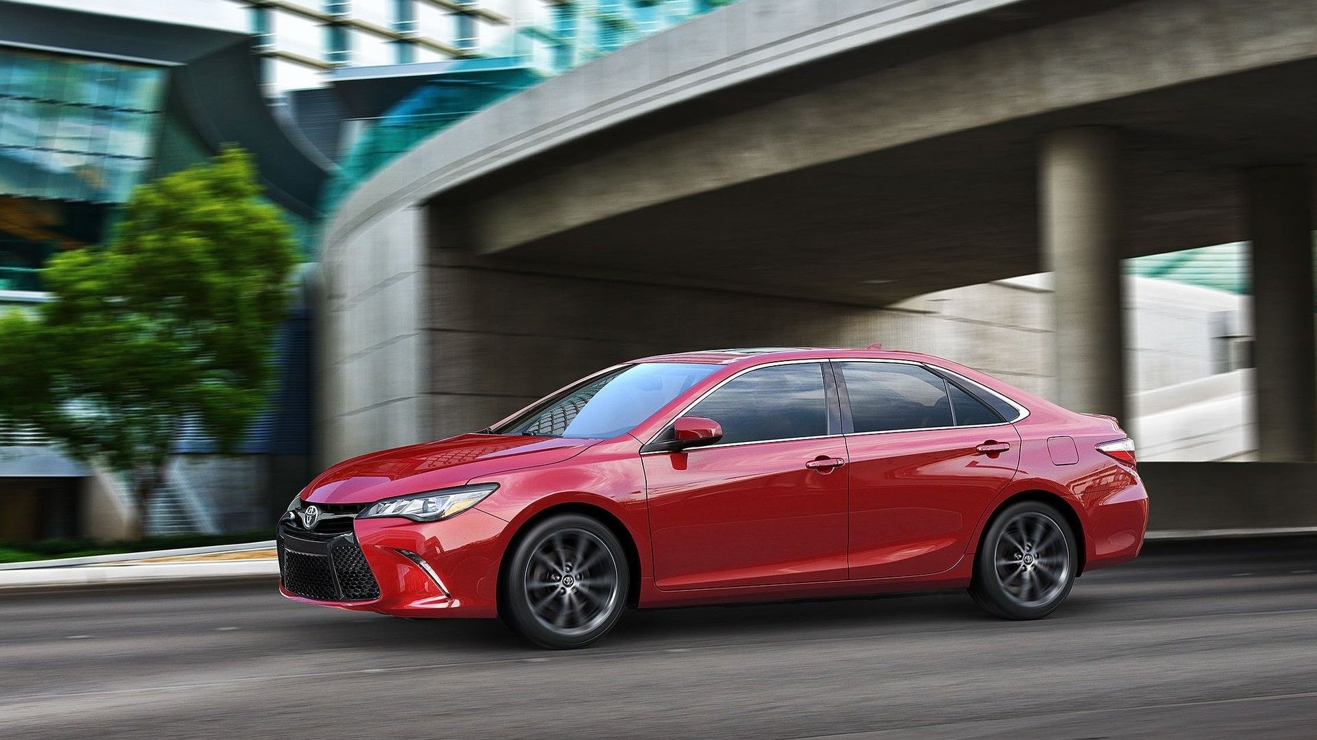 2015 Toyota Camry em vermelho dirigindo na rua da cidade