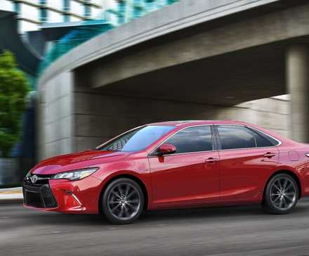 2015 Toyota Camry em vermelho dirigindo na rua da cidade