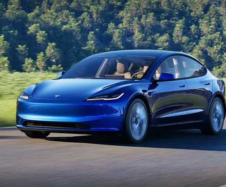 A blue 2025 Tesla Model 3 is driving on the road.