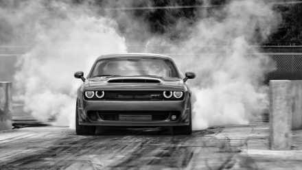 Dodge Challenger realizando burnout, vista de perfil frontal
