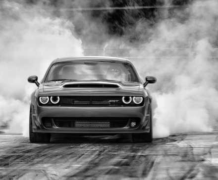 Dodge Challenger realizando burnout, vista de perfil frontal