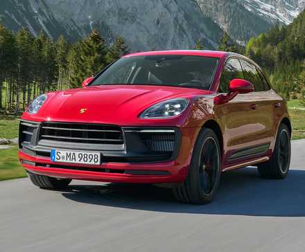 2025 Porsche Macan GTS in red driving on country road with mountains in background