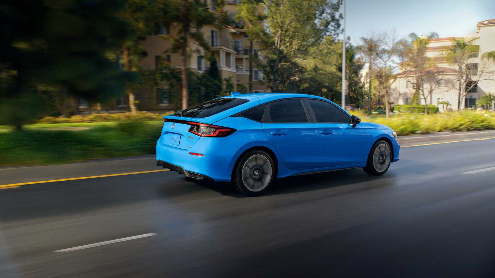2025 Honda Civic Hatchback Sport Touring Exterior híbrido dirigindo em uma estrada