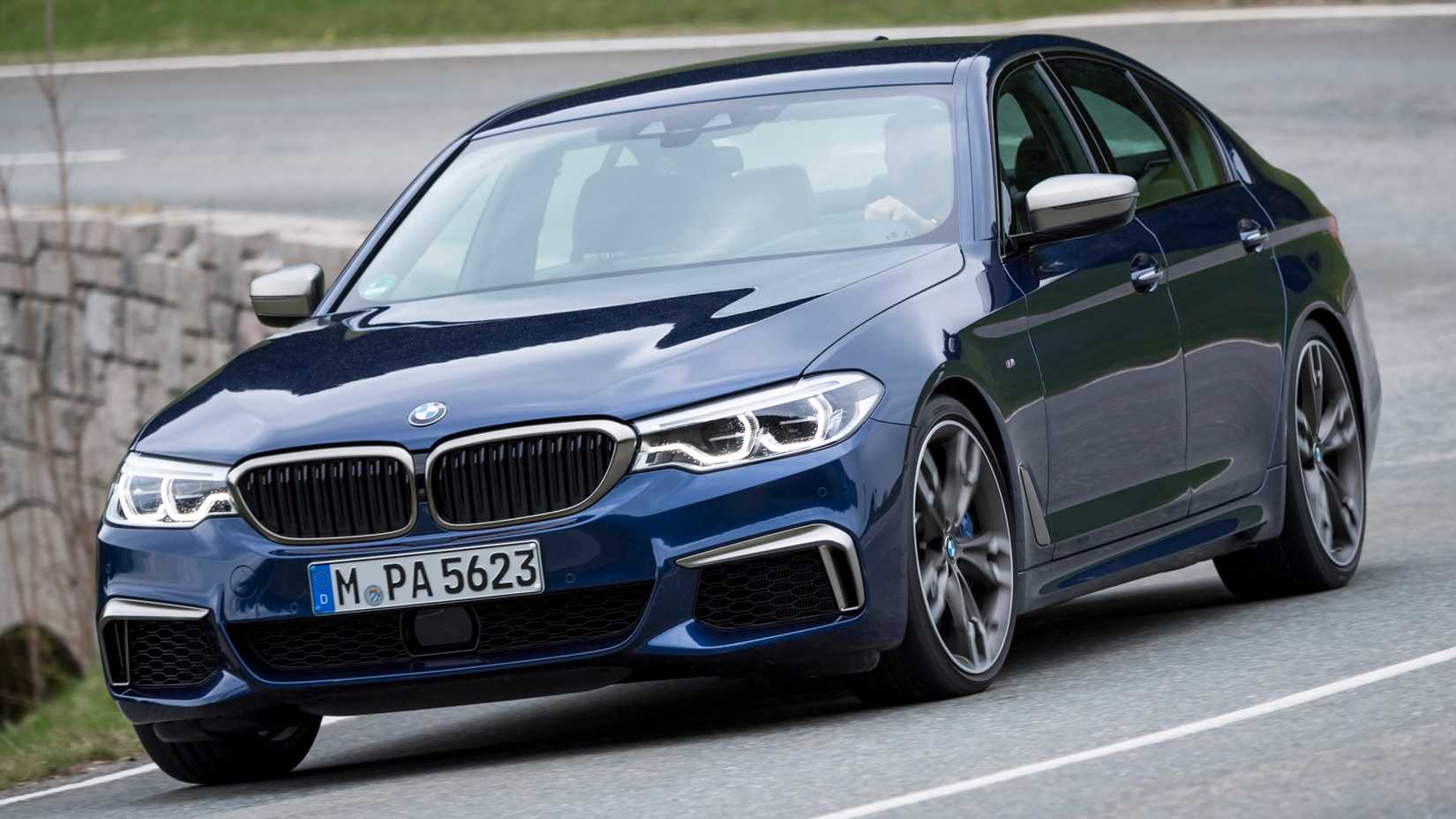 Blue 2020 BMW 5 Series front shot driving down winding road