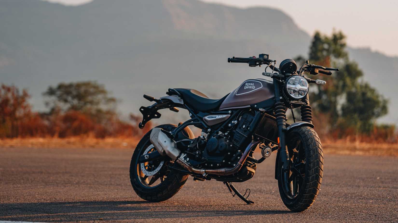 Royal Enfield Guerrilla 450 in Peix Bronze parked on an open road front third quarter view