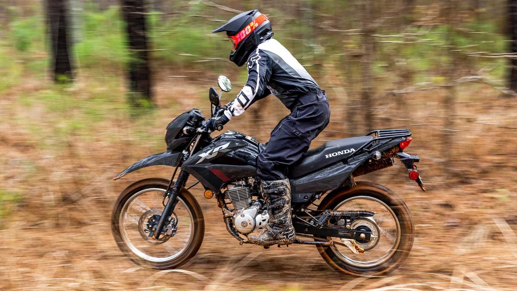 2025 Honda XR150L dual-sport motorcycle accelerating off the road side profile view