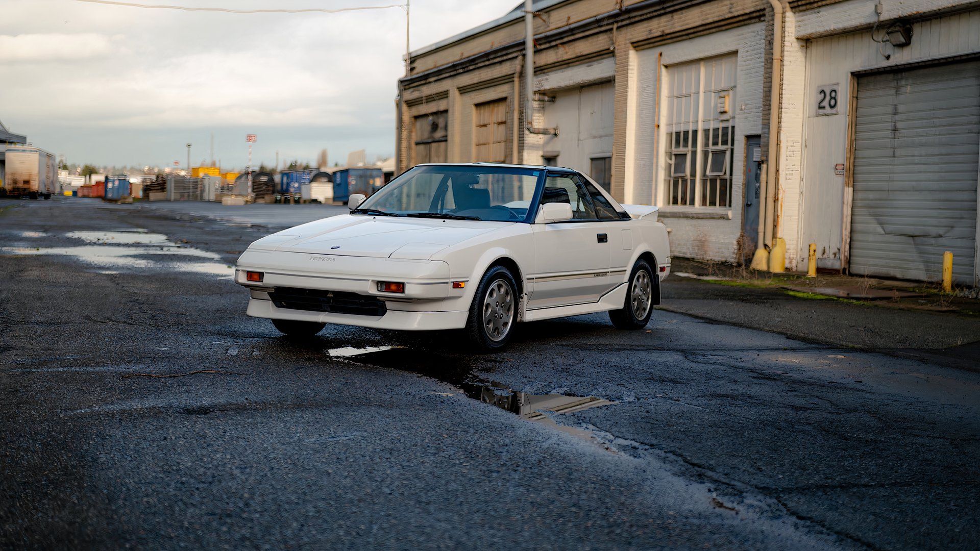 1988 Toyota MR2 Supercharged in white parked outside of garages
