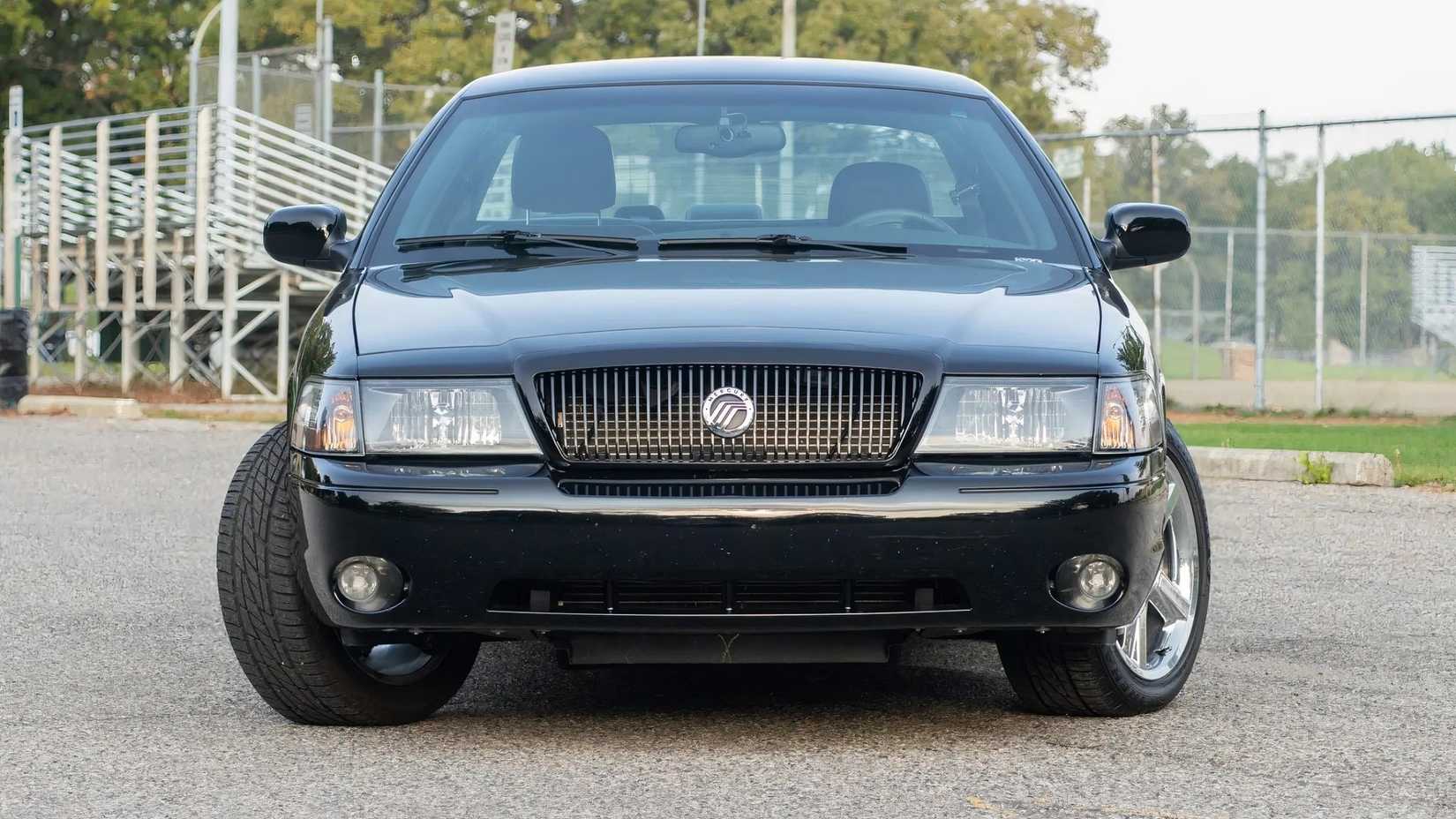 Um Mercury Marauder 2003 mostra sua frente em close-up fotografado por um campo esportivo