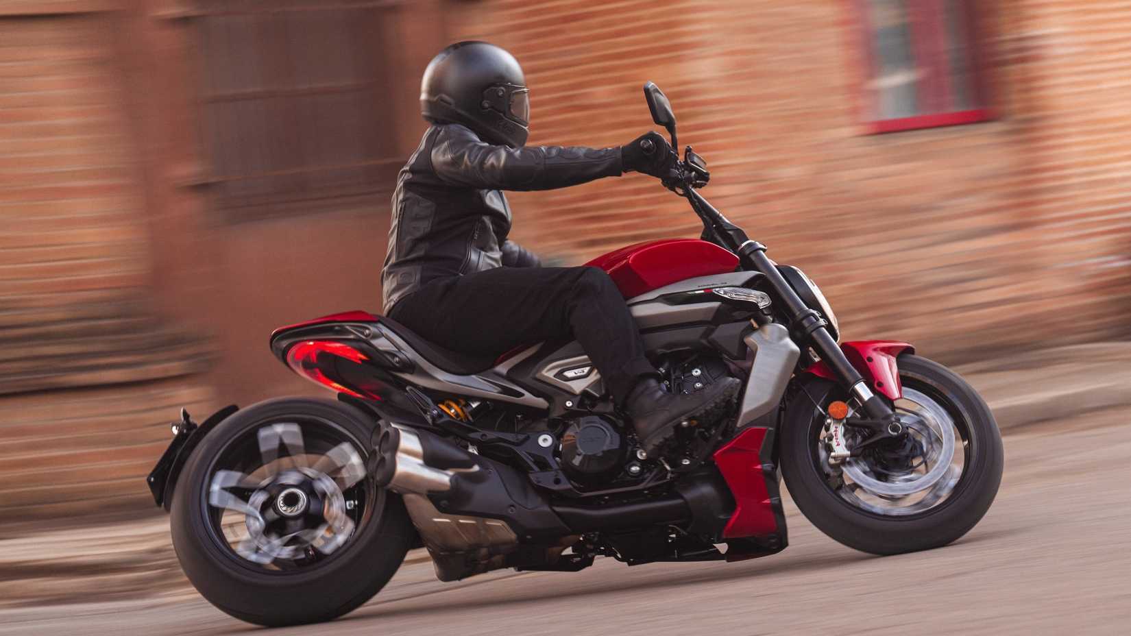 2025 Ducati XDiavel V4 curvando agressivamente vista de perfil lateral