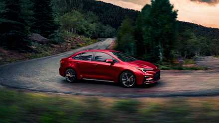 Um pequeno carro híbrido Toyota Corolla Hybrid vermelho.