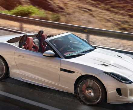 Jaguar F-Type R 2017 em prata dirigindo com teto abaixado em estrada de montanha