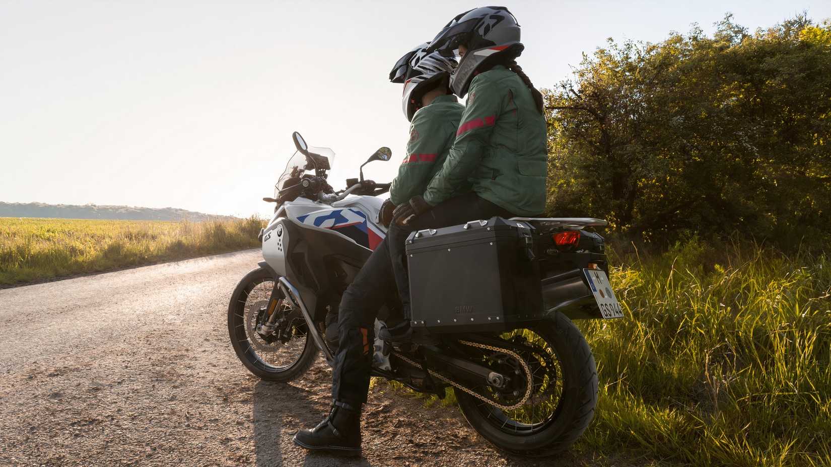 2025 BMW F 900 GS Adventure com piloto e passageiro olhando para uma estrada vazia