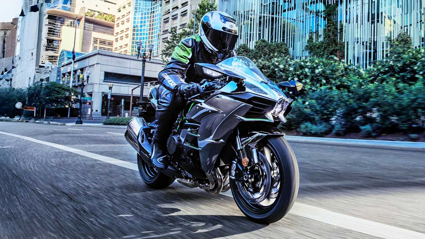 Rider on a Kawasaki Ninja H2 rolling through a city road, front third quarter view