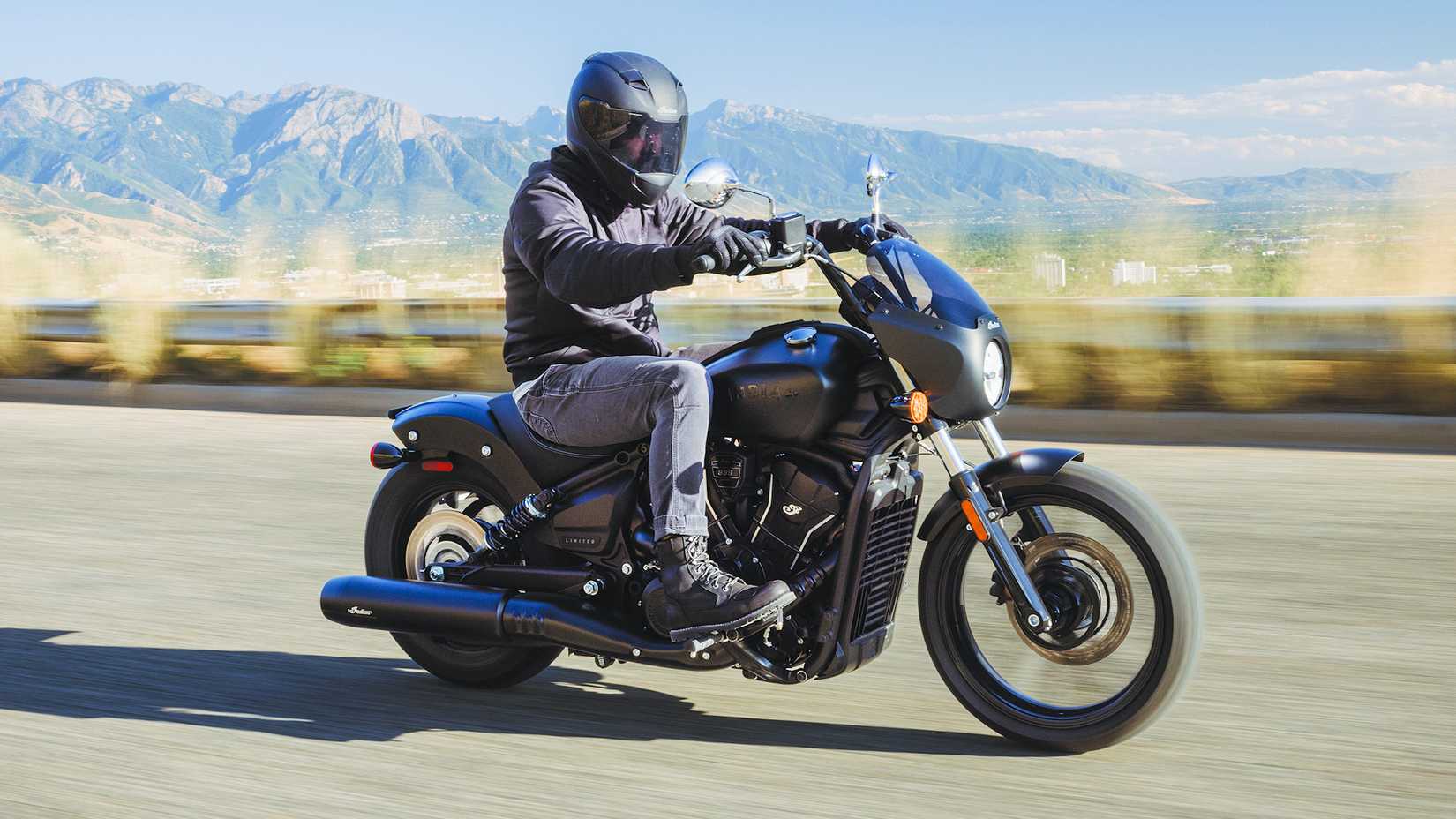 Piloto em um Indian Sport Scout Sixty 2025 andando em uma estrada