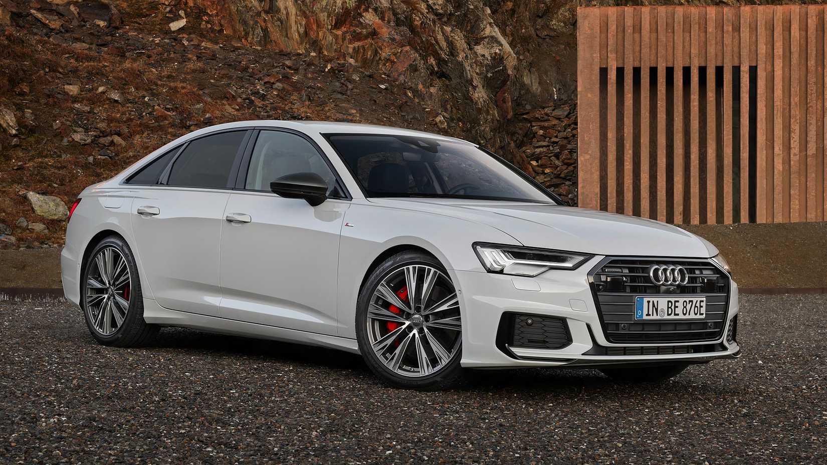 A white 2020 Audi A6 55 TFSI e quattro parked on a gravel pad in front 3/4 view