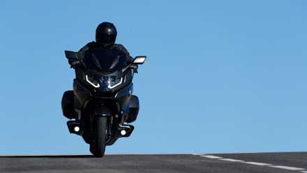 Foto de ação frontal baixa da BMW K 1600 B passando por cima de um cume na estrada