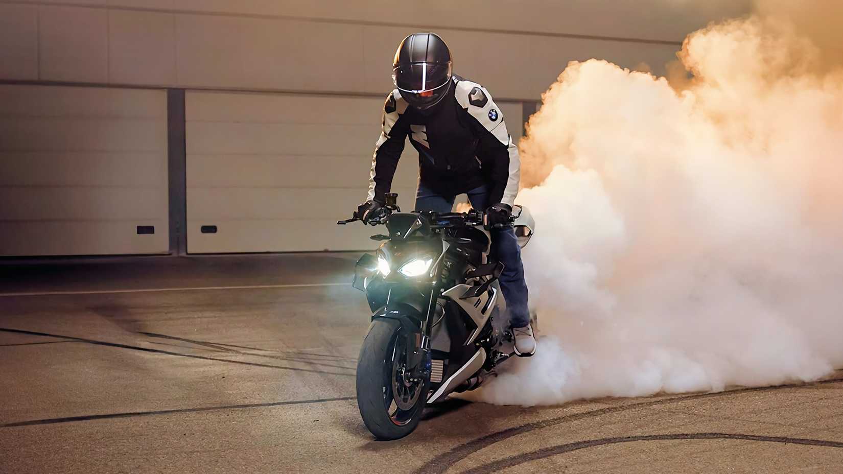 Piloto em uma BMW M 1000 R 2025 em pé e fazendo um burnout