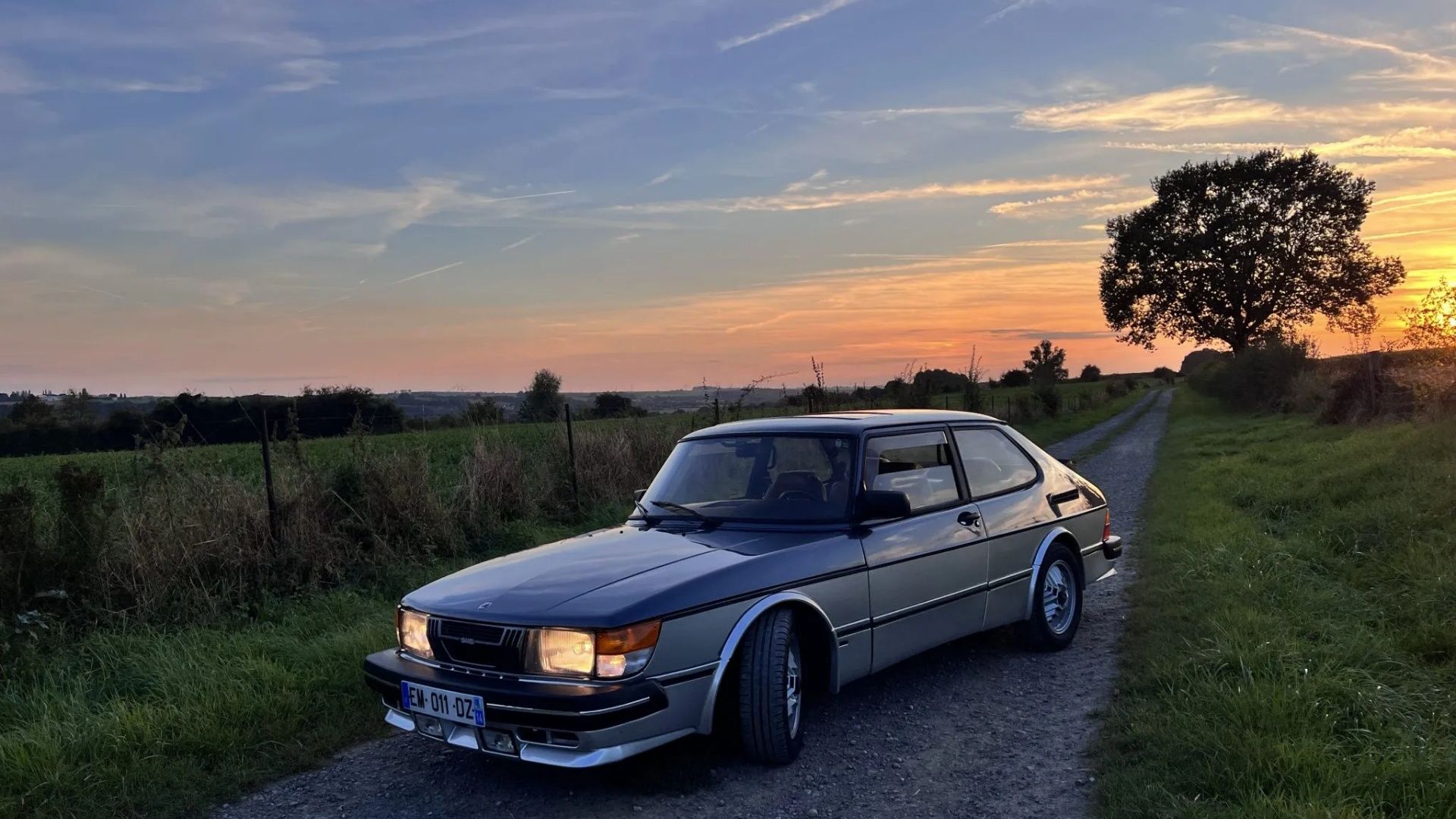1985 Saab 900 Turbo parked on gravel road at sunset