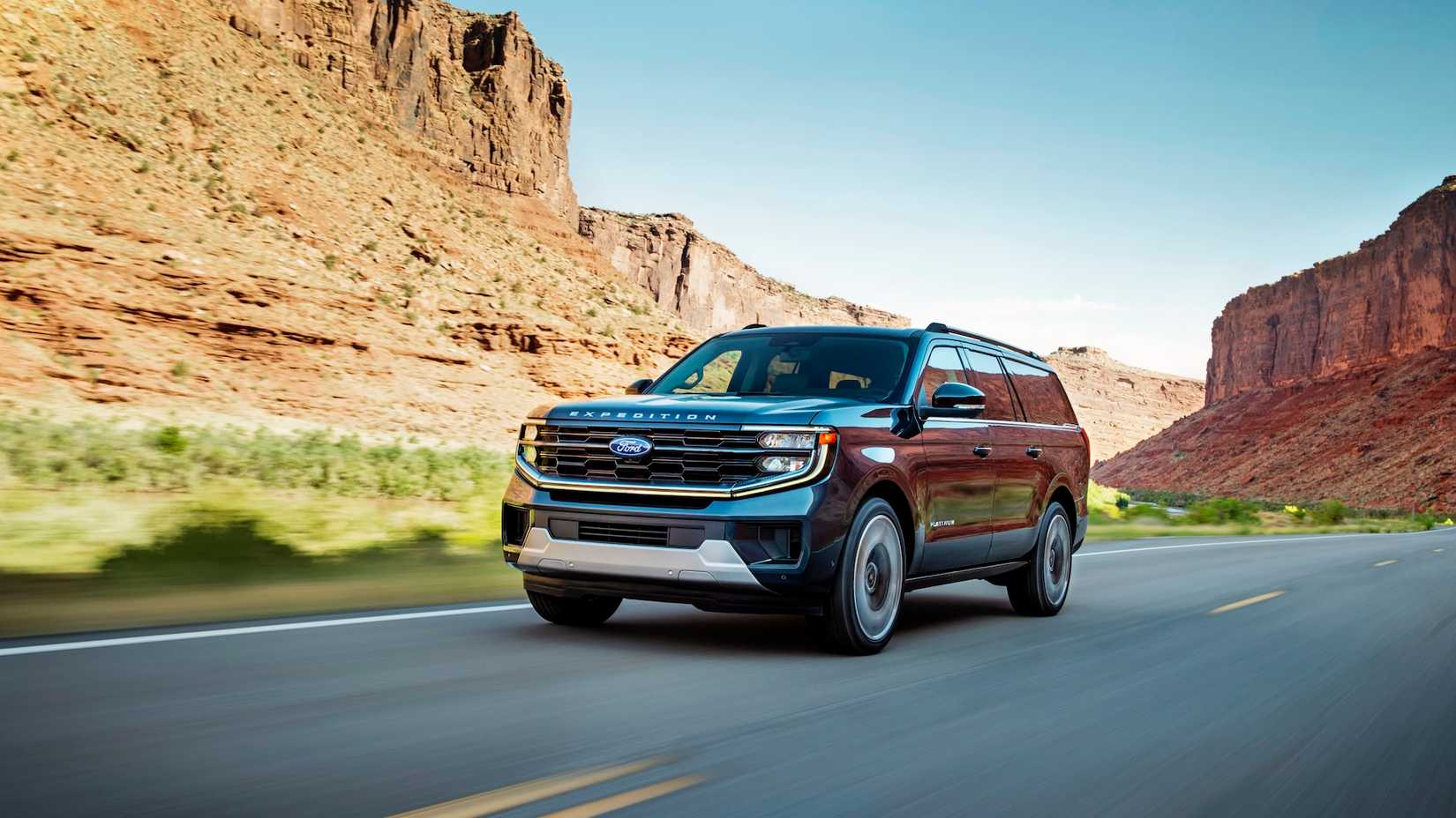 Vista frontal de um Ford Expedition Platinum 2025 dirigindo em uma rodovia rural