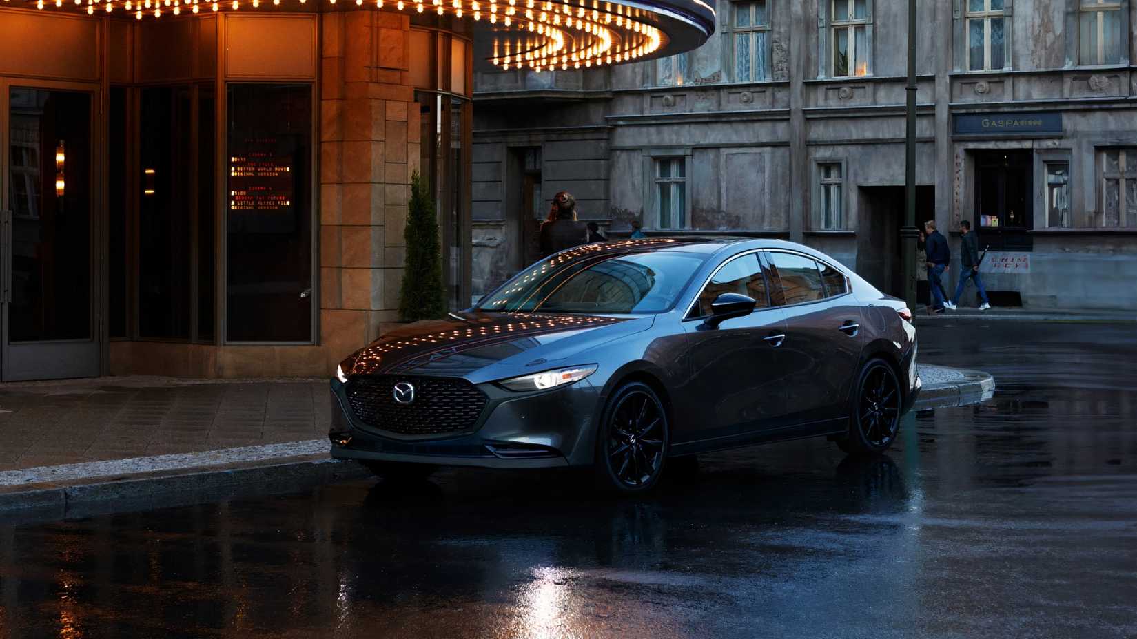2025 Mazda 3 em preto estacionado na rua da cidade com faróis acesos