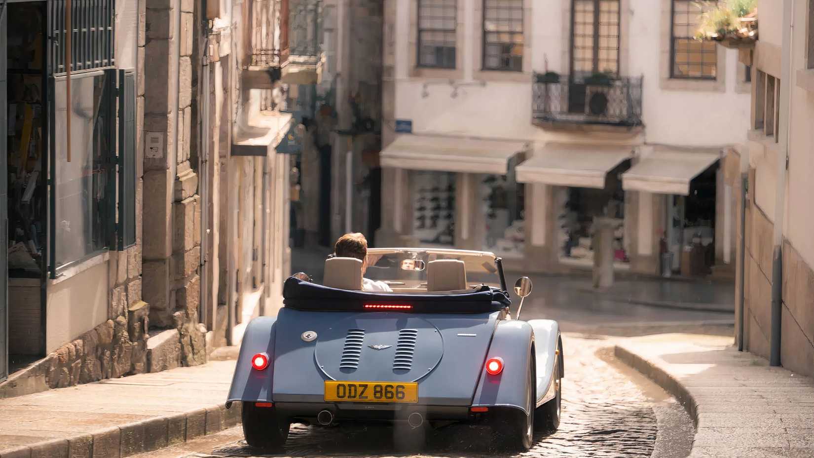 Morgan Plus Four em azul dirigindo pelas ruas da cidade