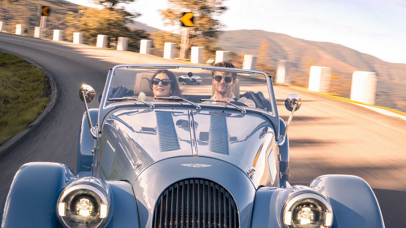 Morgan Plus Four em azul sendo conduzido ao longo da estrada da montanha