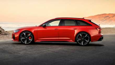 Side shot of a red 2025 Audi RS 6 Avant parked in front of beach