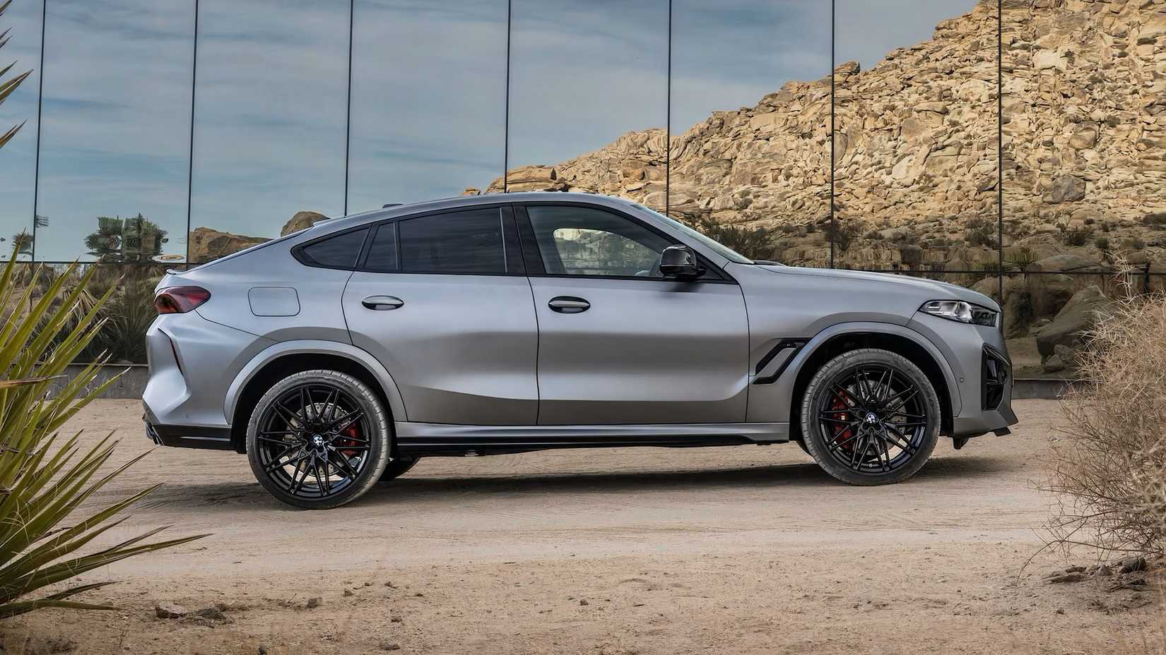 A side-profile shot of a r-gray 2025 BMW X6 M parked off-road
