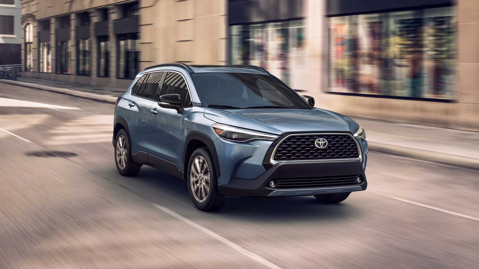 A blue 2025 Toyota Corolla Cross Hybrid front 3/4 shot driving in city