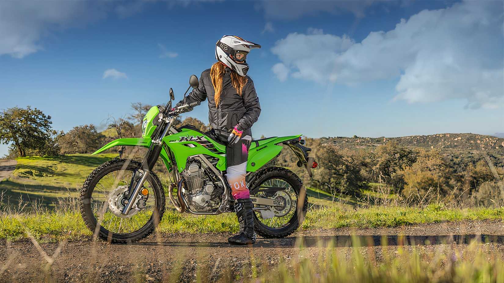 Foto estática da Kawasaki KLX230 com o piloto olhando por cima do ombro