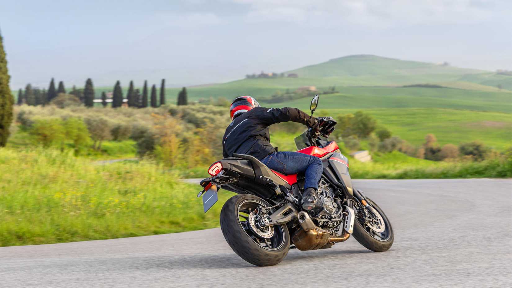 Vista traseira do 2025 Yamaha Tracer 7 curvando nas pastagens