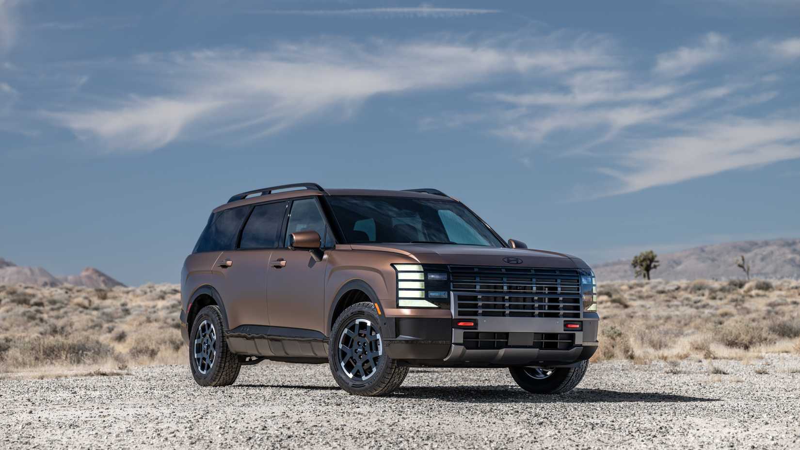 Foto frontal 3/4 de um Hyundai Palisade 2026 de cobre estacionado fora de estrada