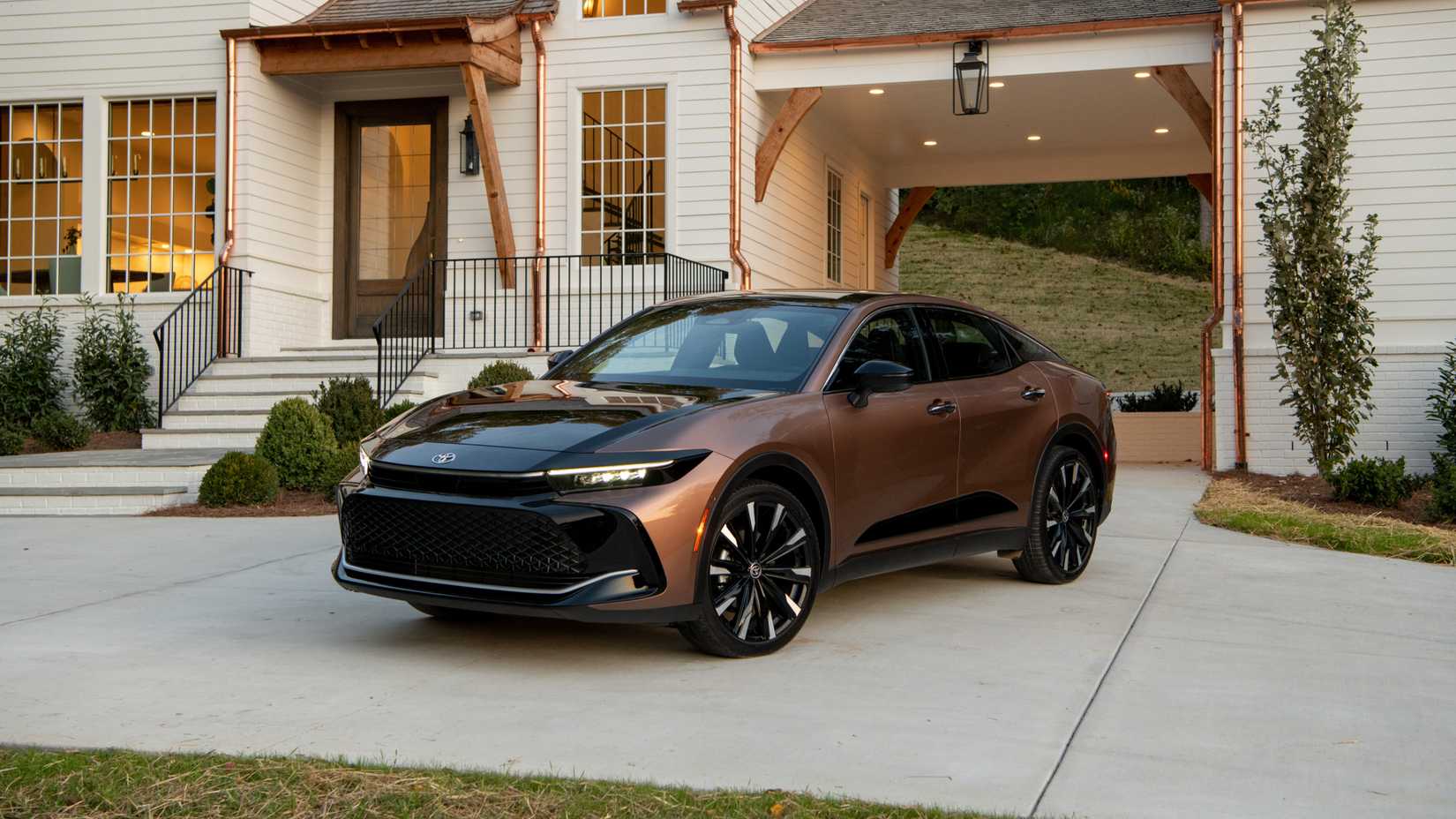 Foto frontal de um Toyota Crown 2026 de cobre estacionado em frente à casa