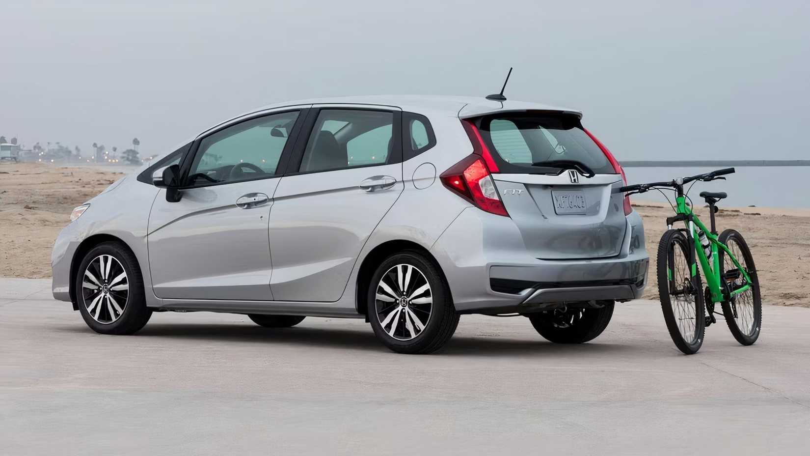 Foto traseira 3/4 de um Honda Fit 2020 estacionado na praia com uma bicicleta