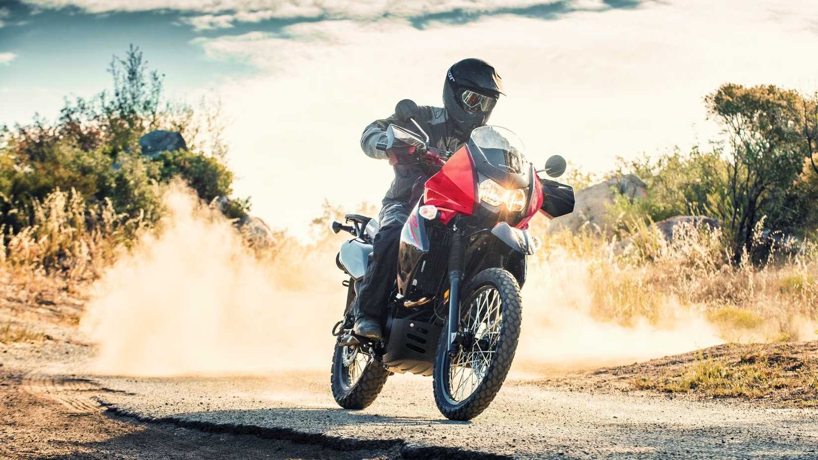 Kawasaki KLR650 pilotada em uma pista de asfalto empoeirada no meio do nada