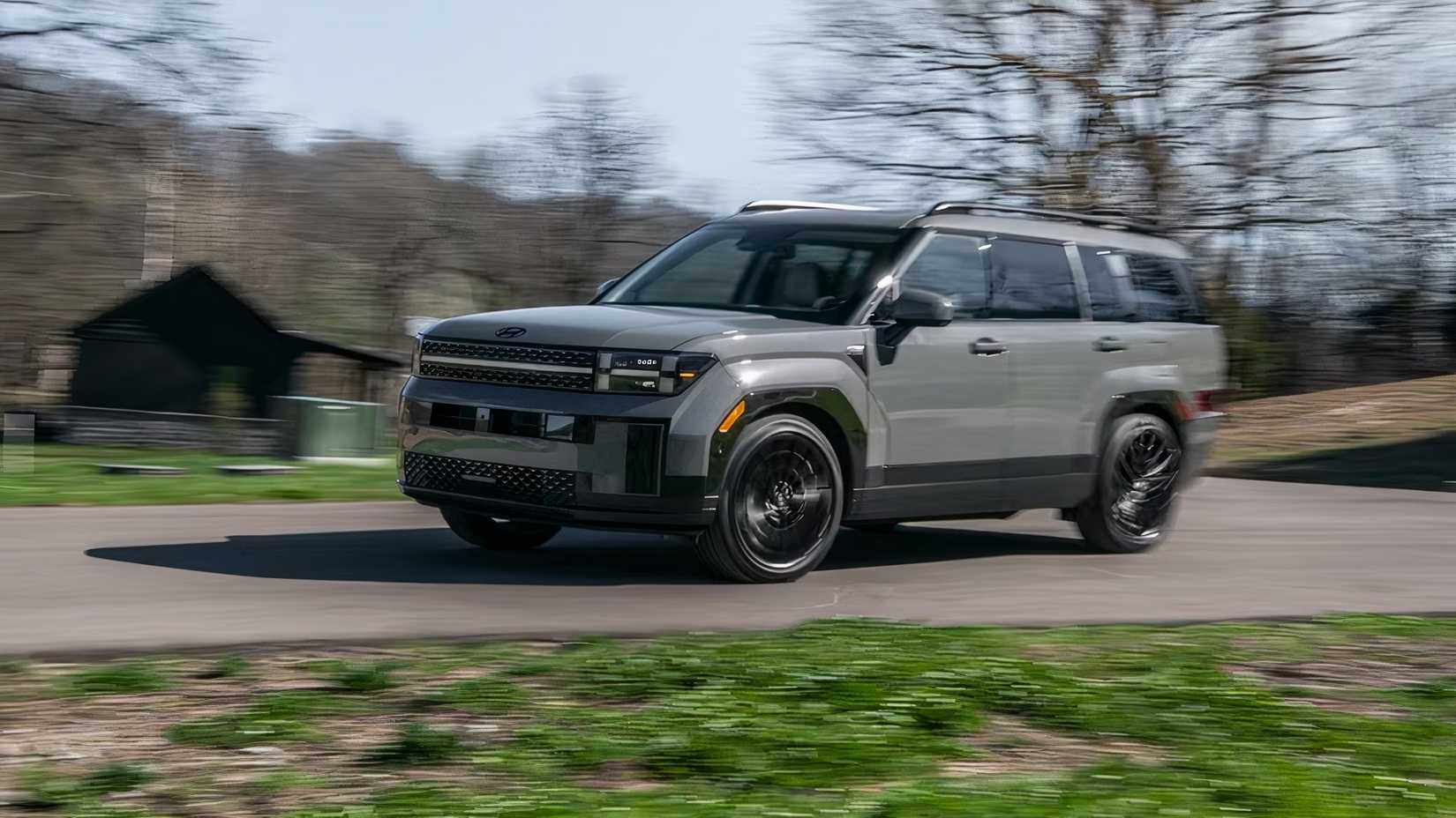 Front shot of a gray 2026 Hyundai Santa Fe accelerating down the road