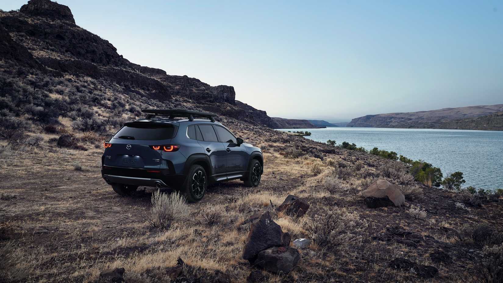 Imagem 3/4 traseira de um Mazda-CX-50 em Polimetal-Cinzento estacionado fora de estrada