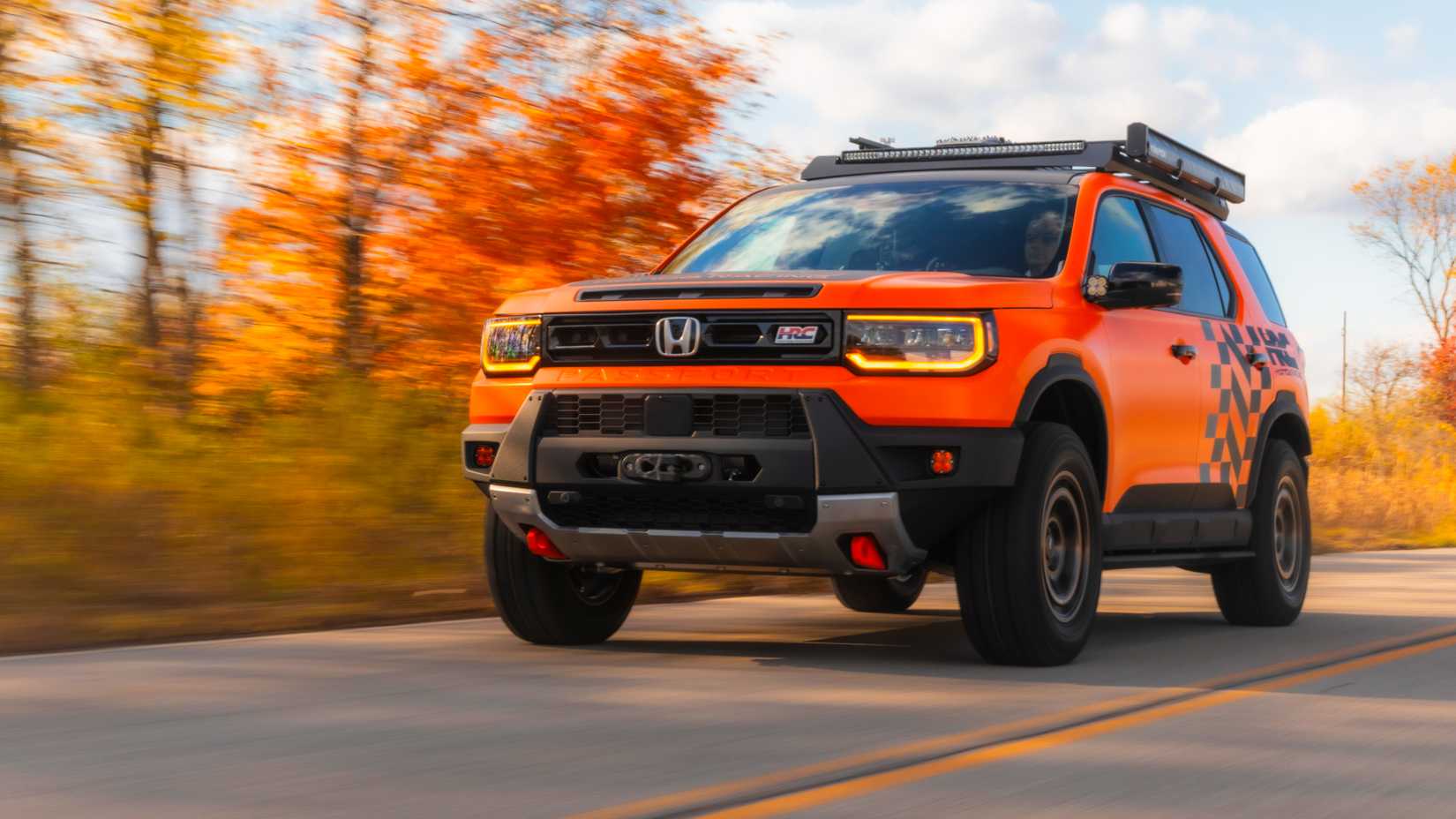 A 2026 Honda Passport Trailsport HRC driving down a country road in the fall