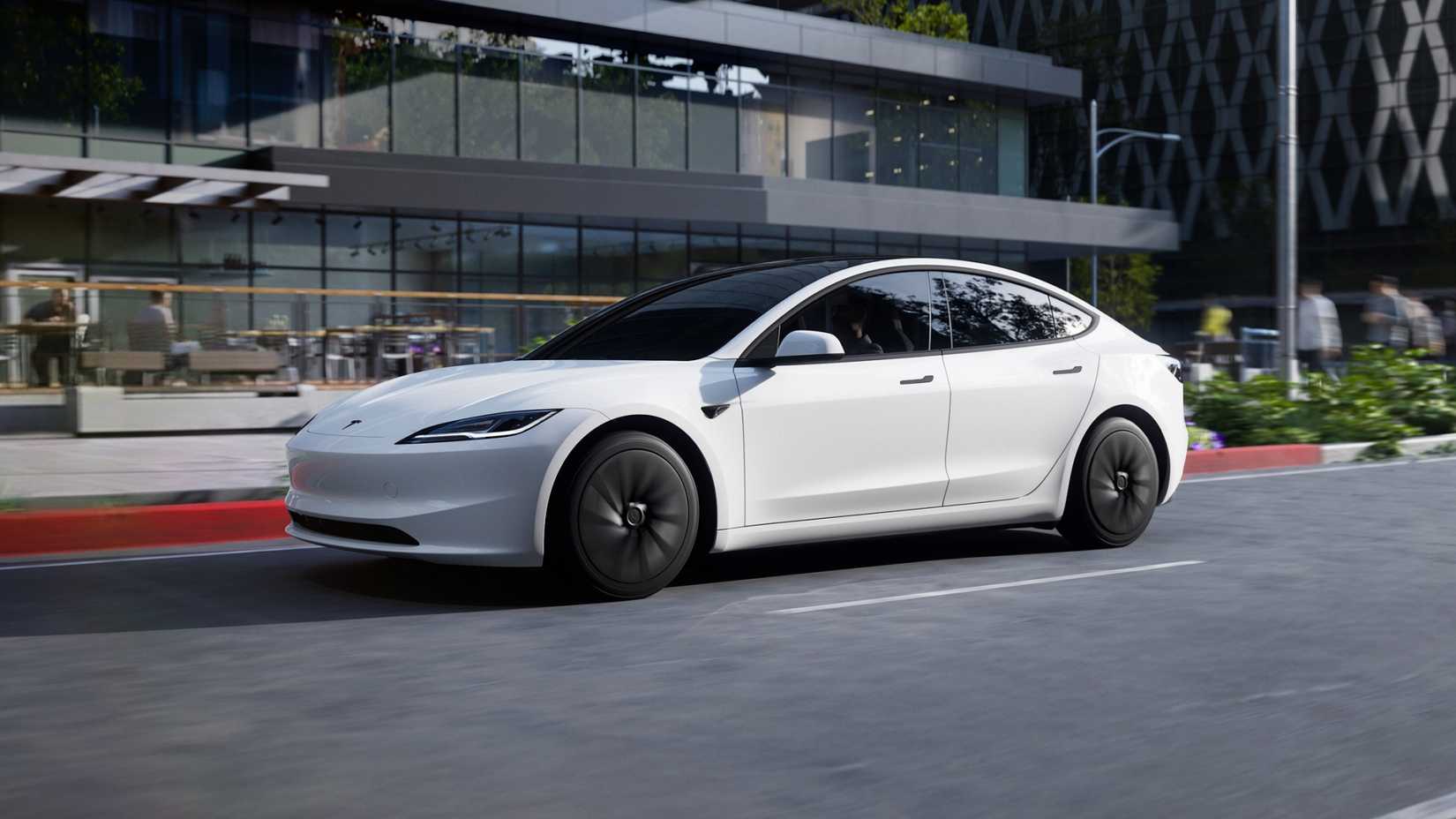 A white Tesla Model 3 Standard driving on the road