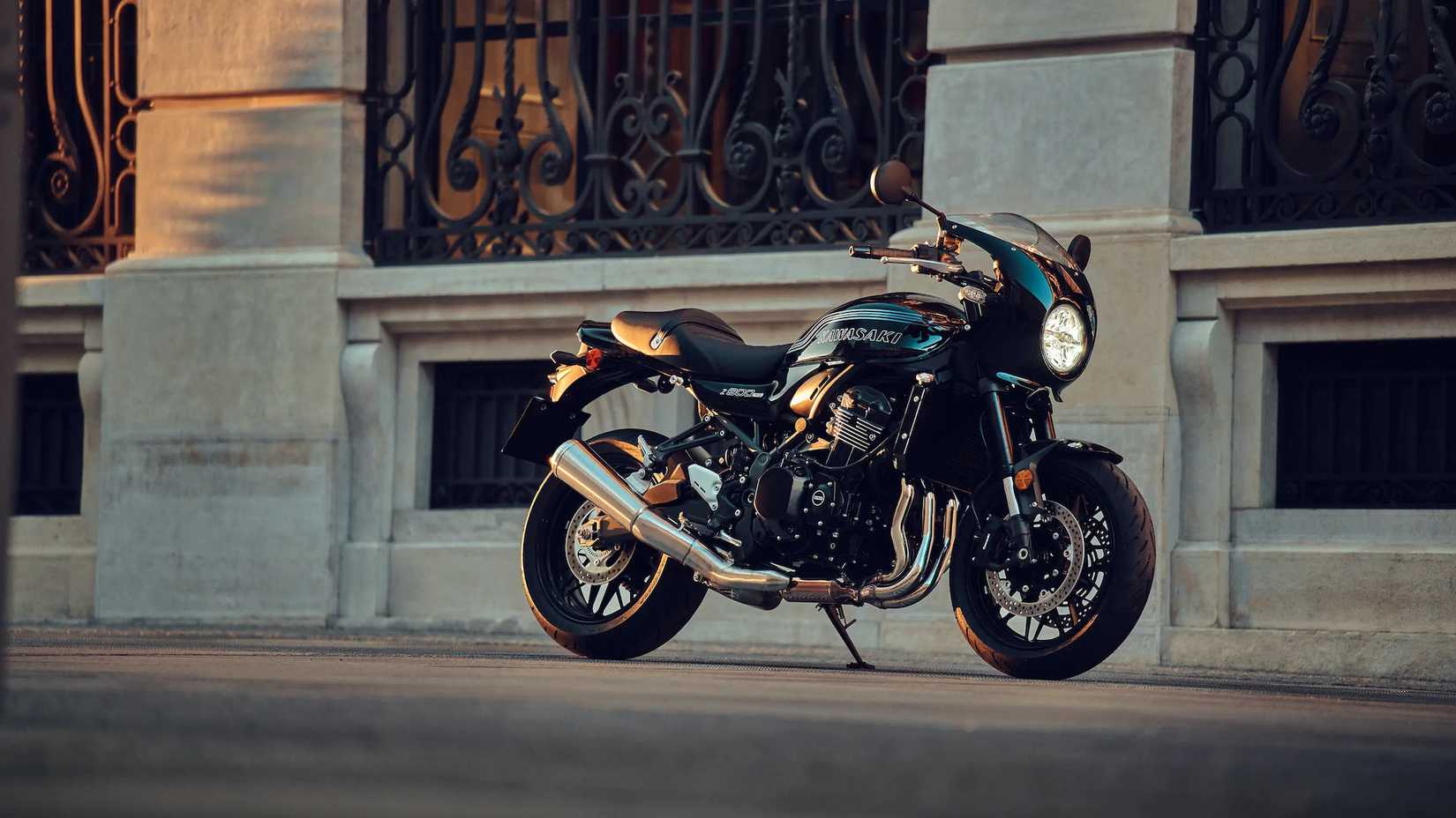 Low angle static shot of black and green Kawasaki Z900RS cafe parked in front of old style architectural building