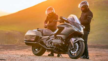 Piloto e passageiro ao lado de uma Honda Gold Wing 2026 estacionada na beira da estrada